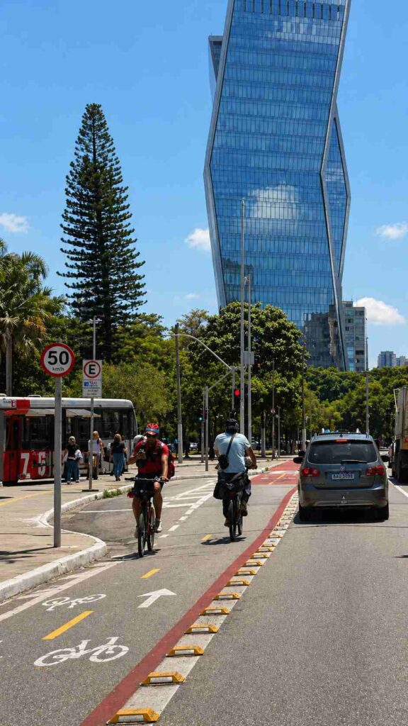 Mobilidade urbana em Pinheiros com ciclovia, carros e prédio moderno ao fundo em São Paulo Mobilidade urbana em Pinheiros com ciclovia, carros e prédio moderno ao fundo em São Paulo