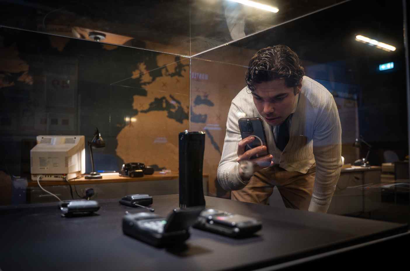 Visitante observa objetos e evidências em ambiente investigativo da exposição