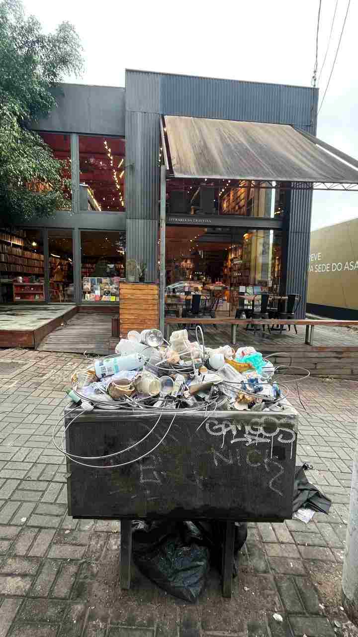 Sacos e resíduos junto a lixeira pública na Rua dos Pinheiros